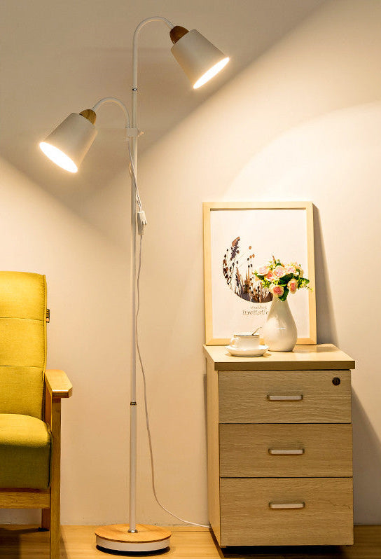 Living room with a green armchair, floor lamp, and side table with a vase and picture frame.