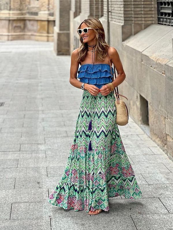 Woman wearing a blue ruffled top and green patterned skirt in an urban setting