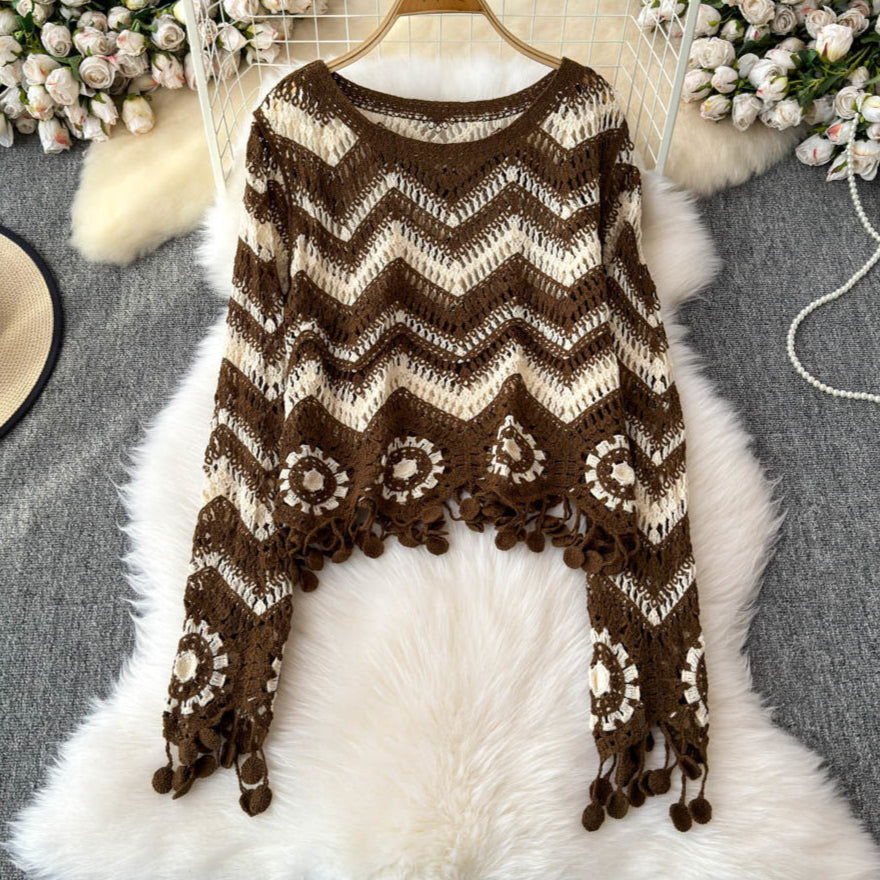 Brown and beige patterned poncho on a white fur surface with floral decorations in the background