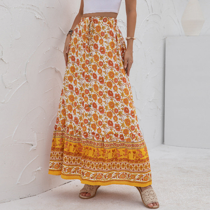 Person wearing a long floral skirt with orange and yellow patterns against a white background