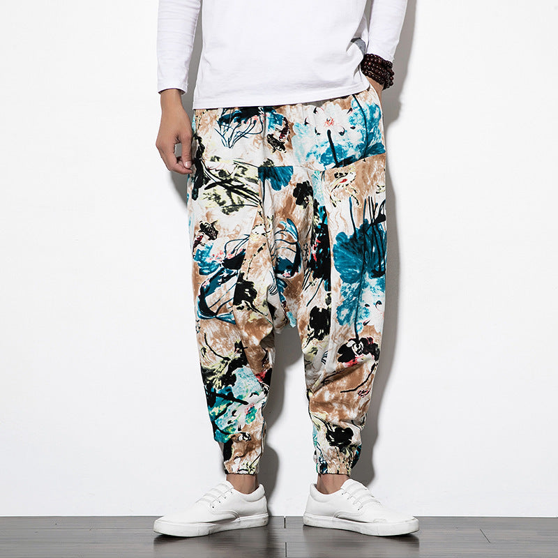 Person wearing floral-patterned pants and white sneakers on a plain background