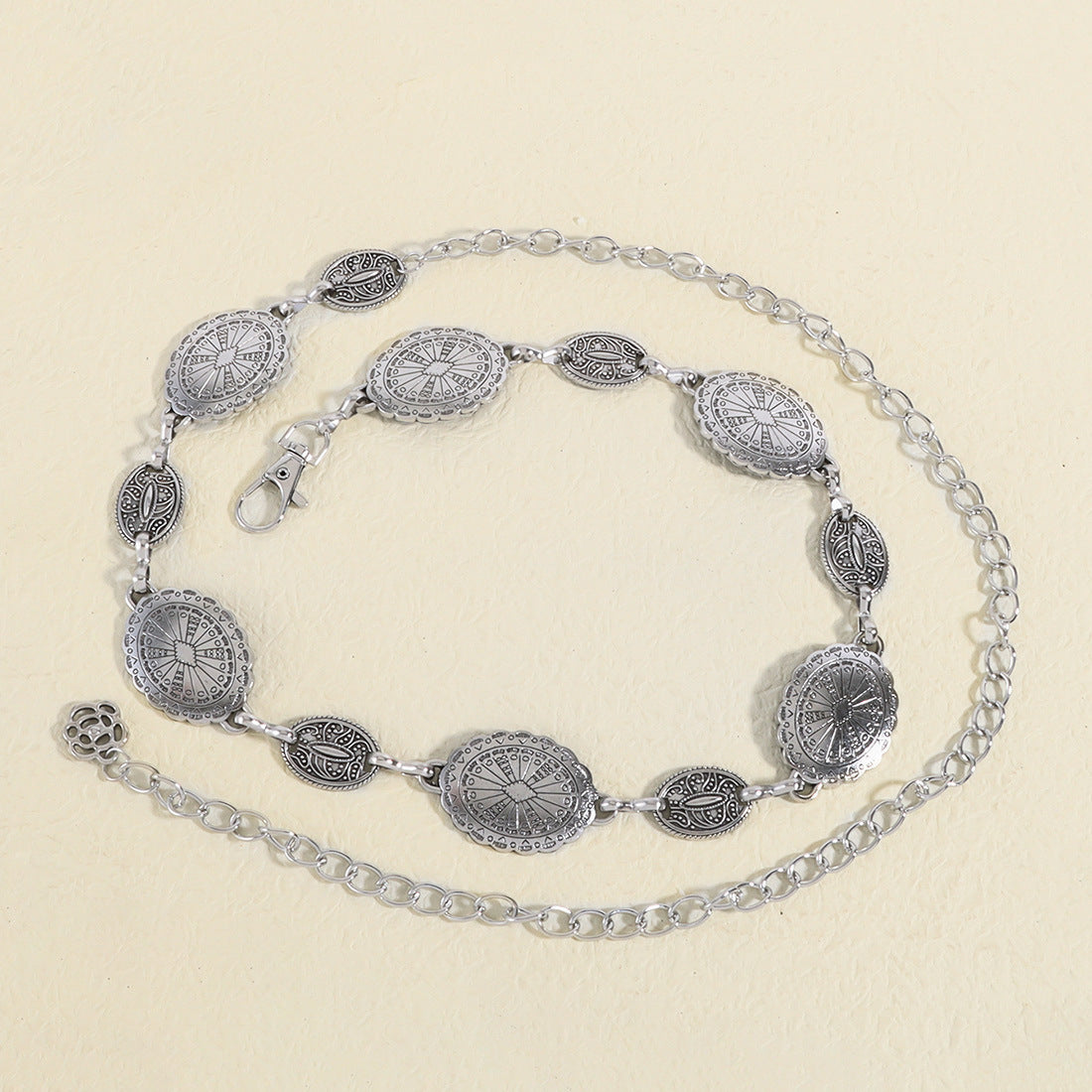 Silver belt with decorative metal plates on a beige background