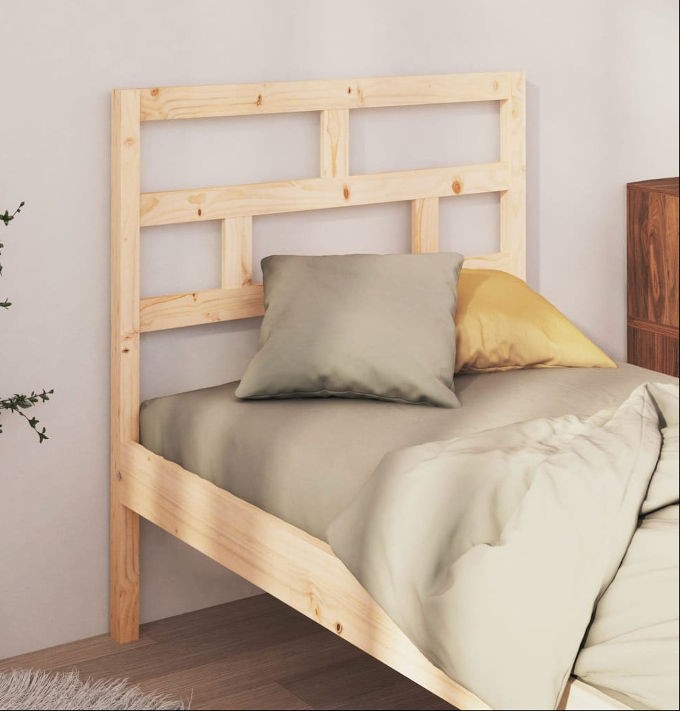Wooden bed with bedding and pillows against a neutral wall