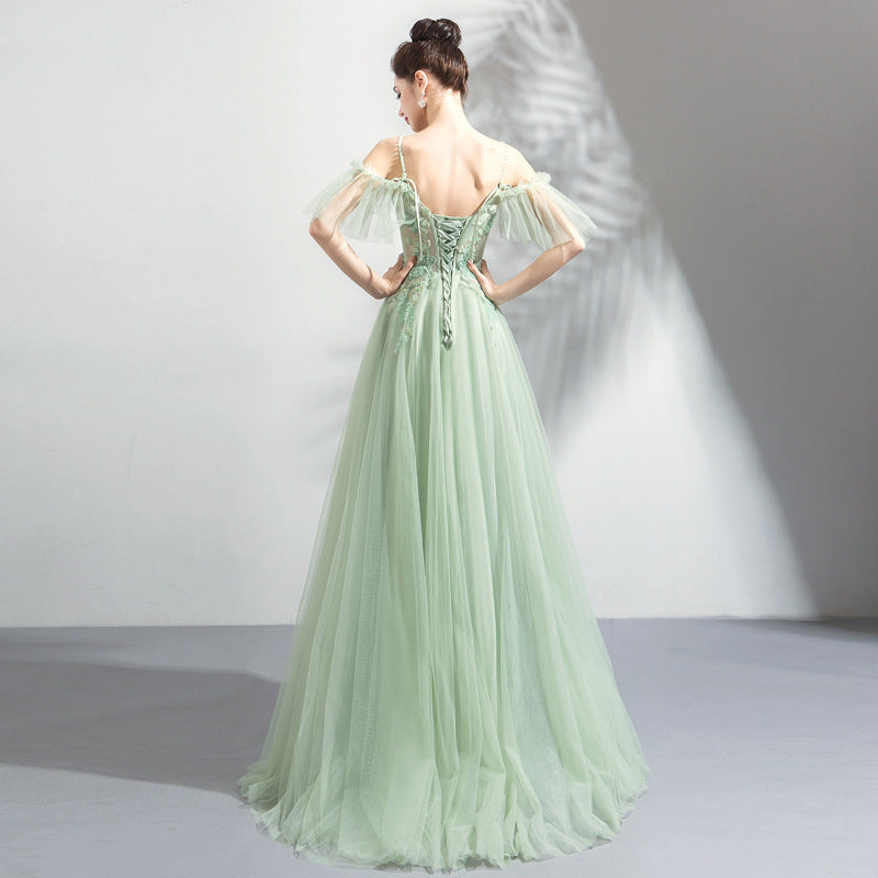 Woman wearing a light green evening gown with a plain background