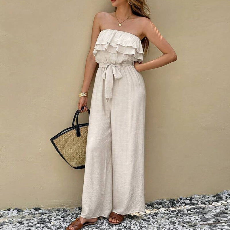 Woman wearing a strapless ruffled jumpsuit with a beige background