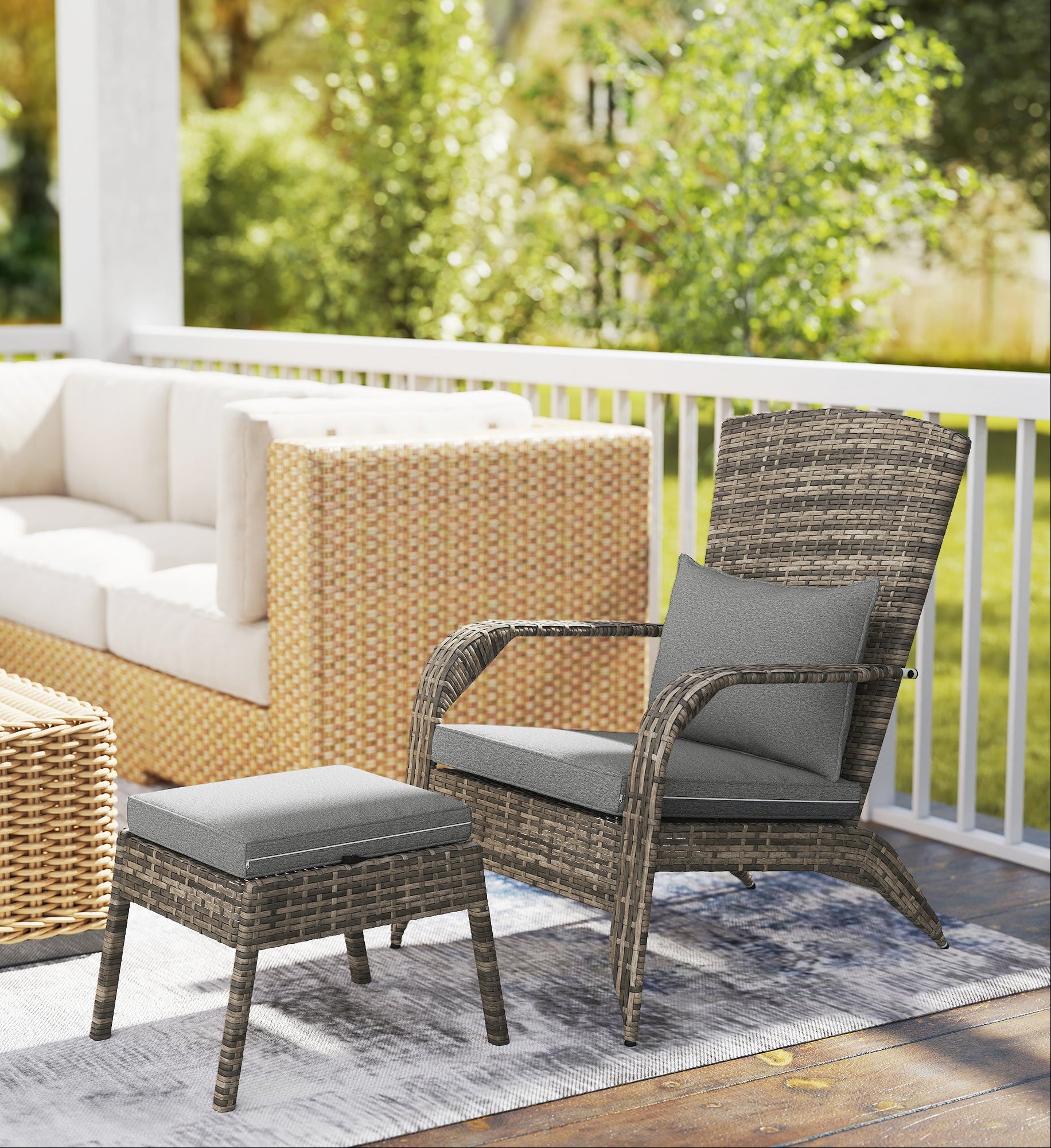 Outdoor patio set with wicker chairs, ottoman, and sofa on a deck with greenery in the background.