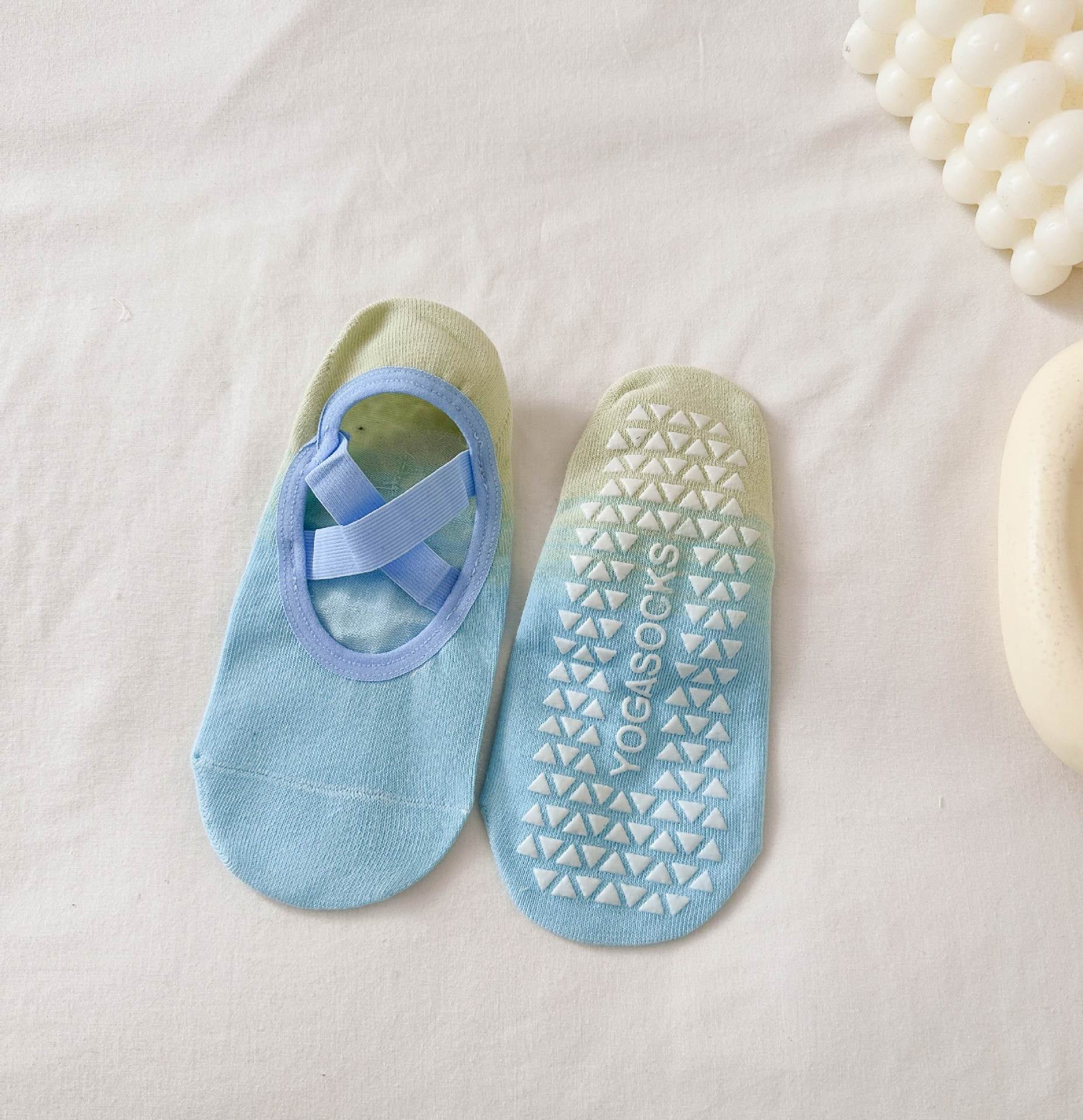Pair of blue and green yoga socks with textured sole on a light background