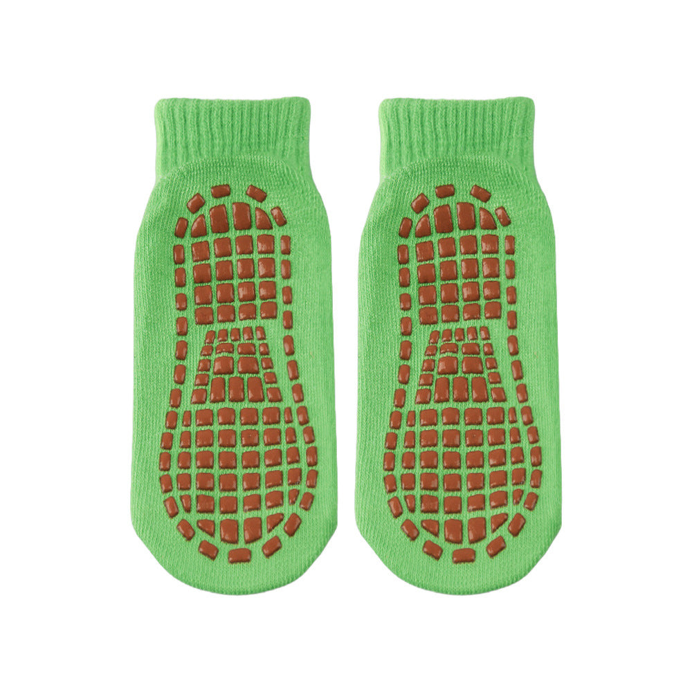 Pair of green socks with brown textured sole on a white background