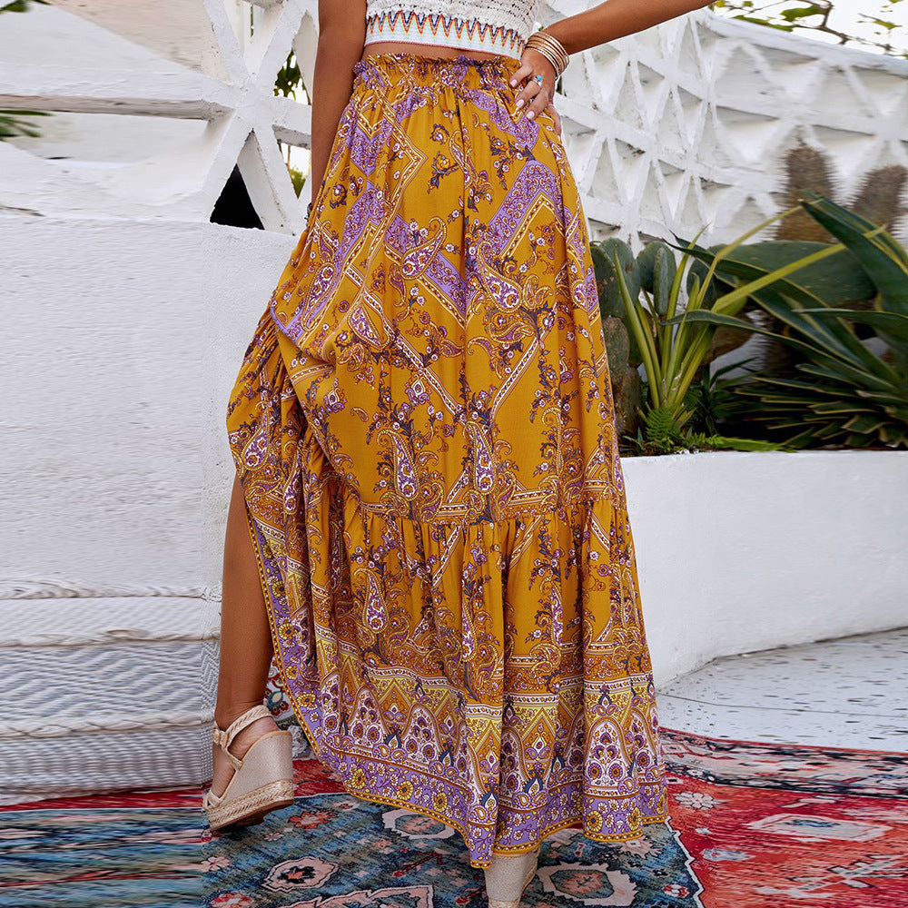 Person wearing a patterned yellow and purple skirt on a patio with plants and furniture.