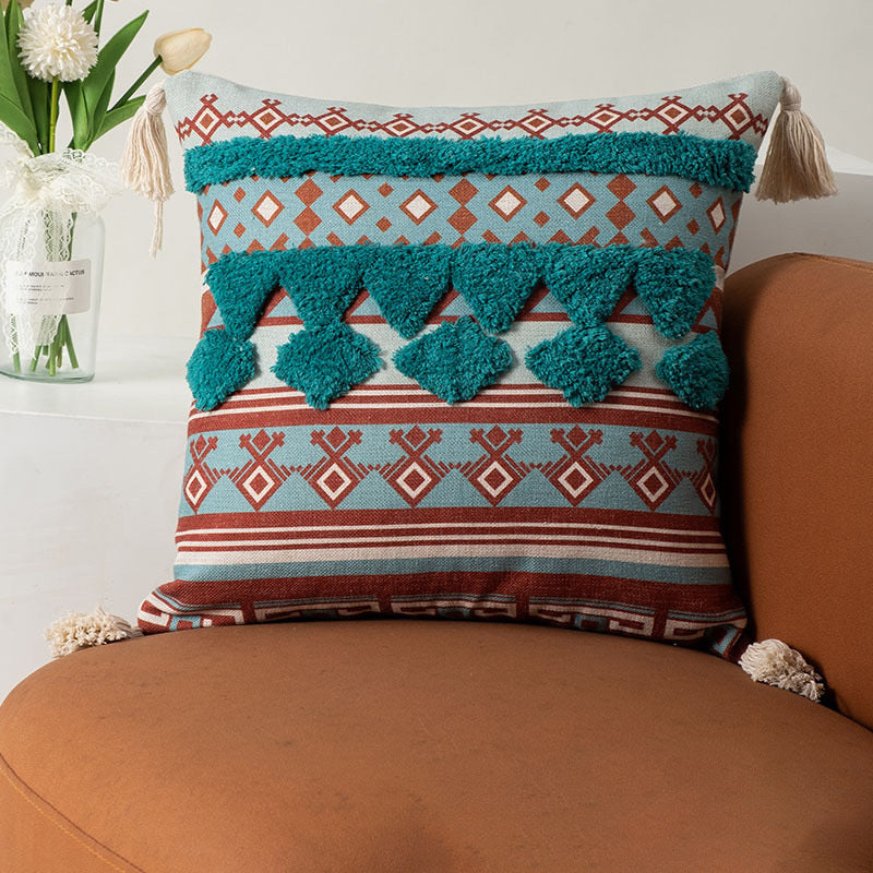 Decorative pillow with geometric pattern and tassels on a brown couch