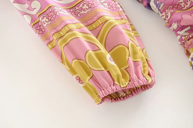 Pink and gold patterned baby bloomers on a white background
