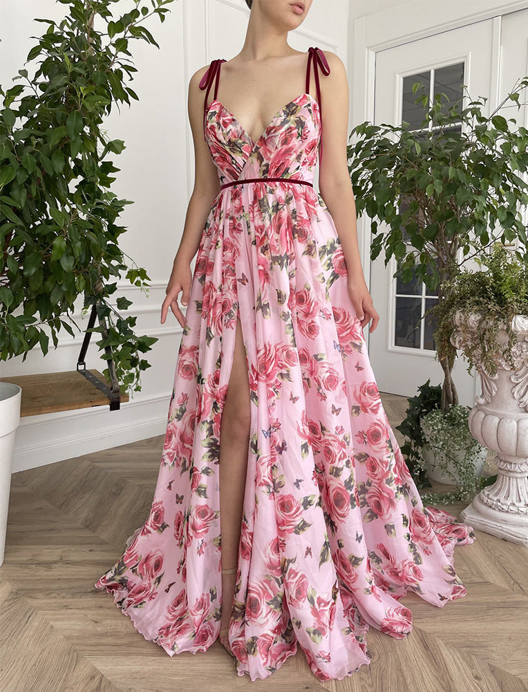 Woman wearing a pink floral dress with a high slit in a room with plants.