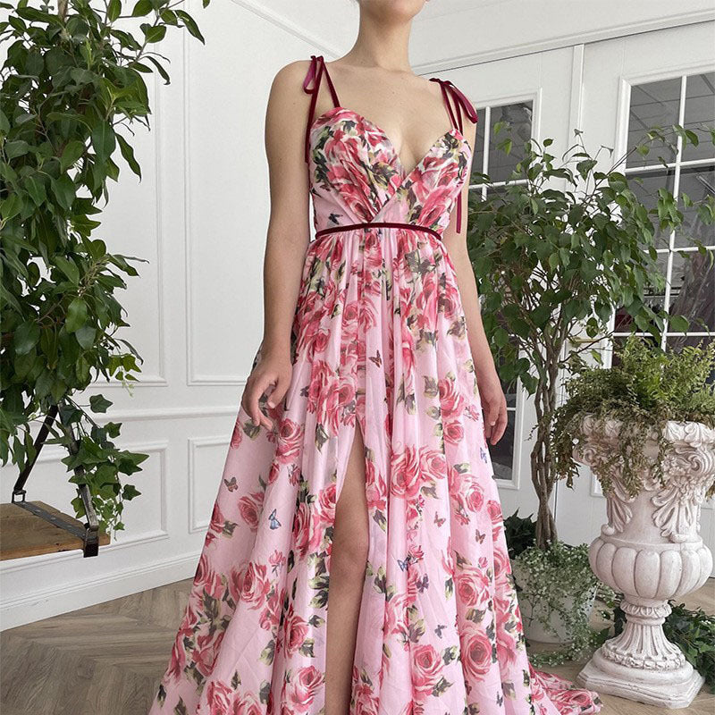 Woman wearing a pink floral dress with a high slit in a room with plants.