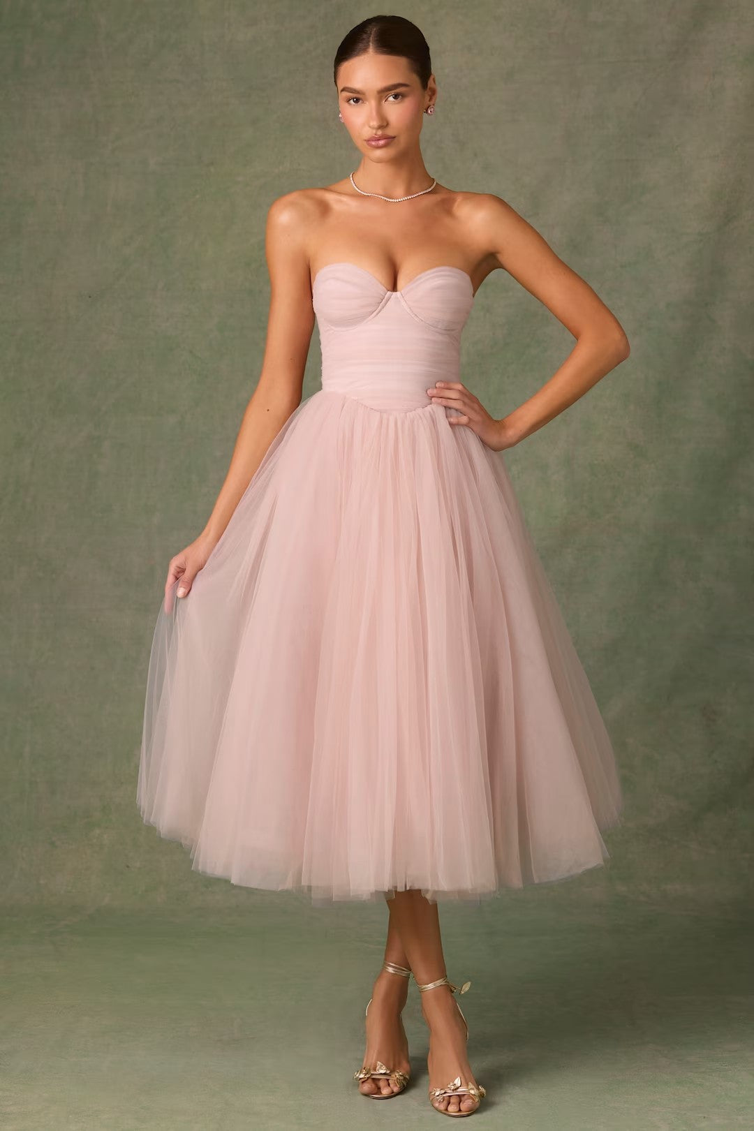 Woman wearing a pink strapless dress against a green background