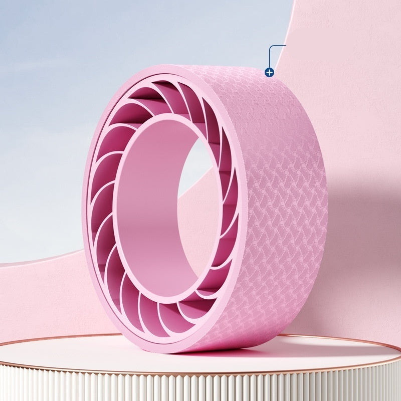 Pink yoga wheel on a light pink background with a blue label indicating 'Yoga Wheel'.
