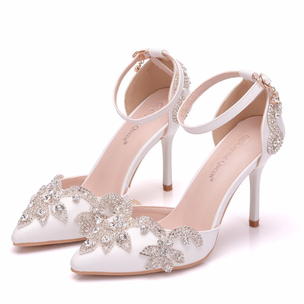 White high-heeled shoes with silver floral embellishments on a white background