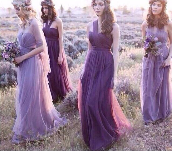 Four women in long, flowing dresses standing in a field of lavender.