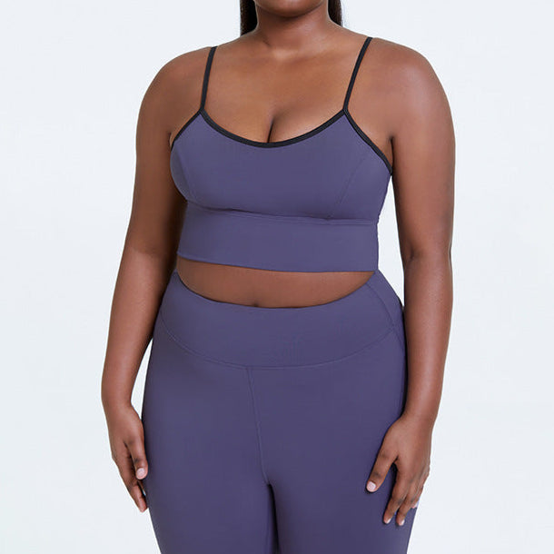 Woman wearing a purple sports bra and leggings on a light gray background