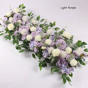 Light purple and white floral arrangement with green leaves on a light gray background