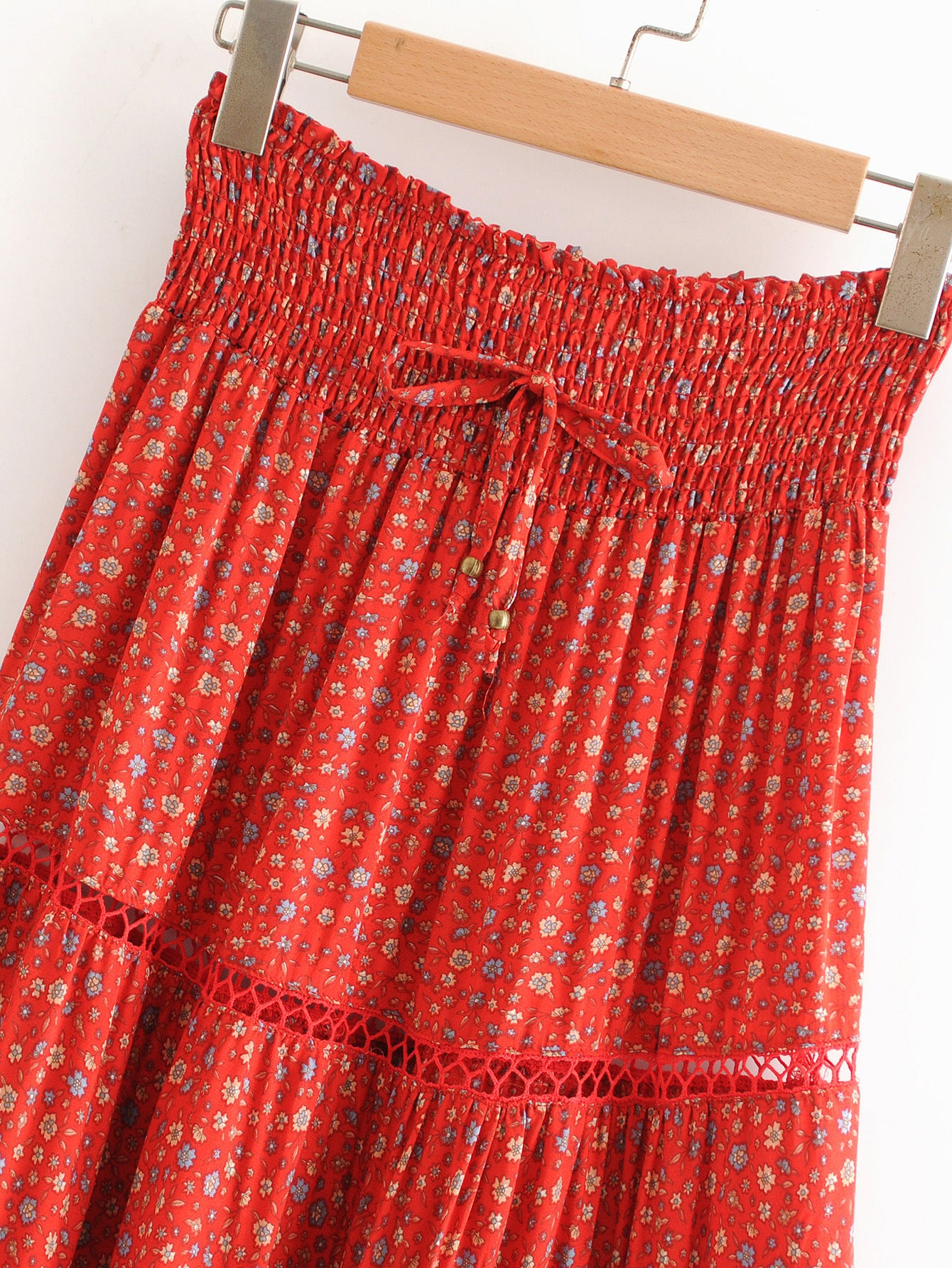 Red floral skirt on a wooden hanger against a white background