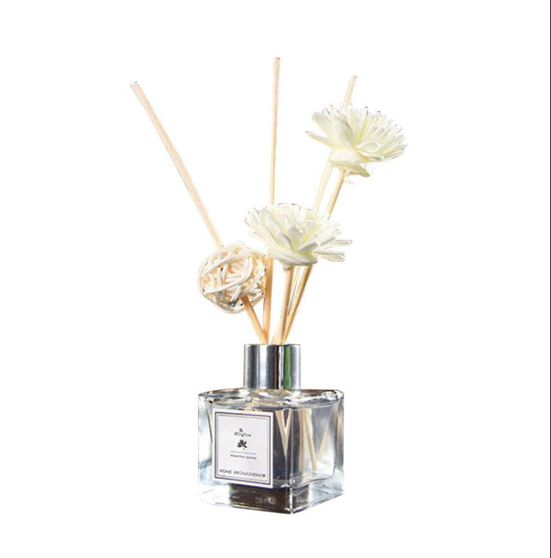 Reed diffuser with floral elements on a white background