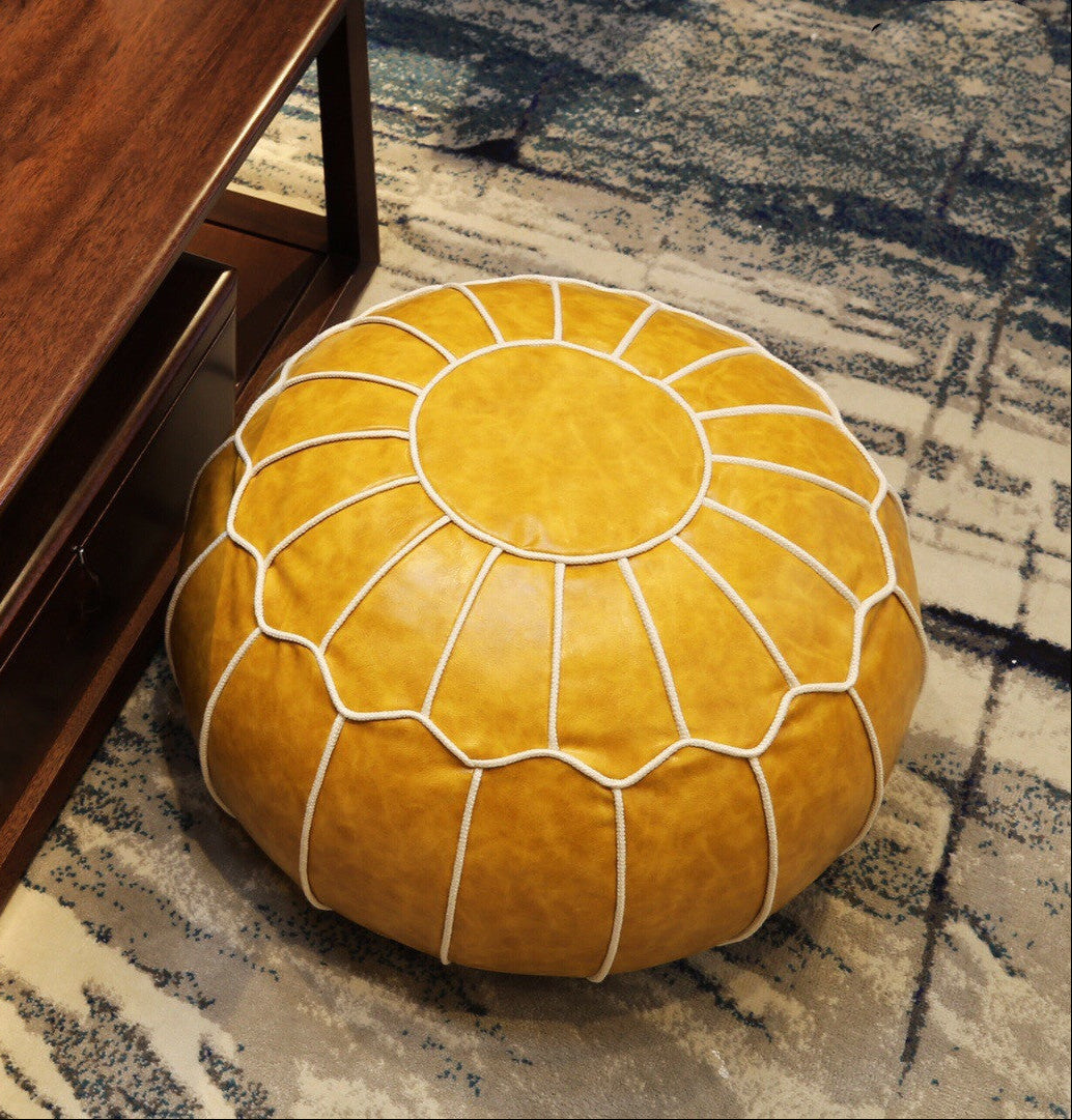 Yellow leather pouf on a patterned rug next to a wooden piece of furniture