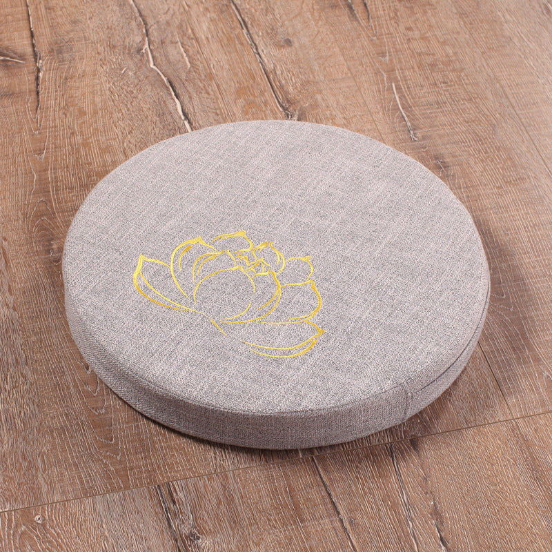 Round gray cushion with yellow floral design on a wooden floor