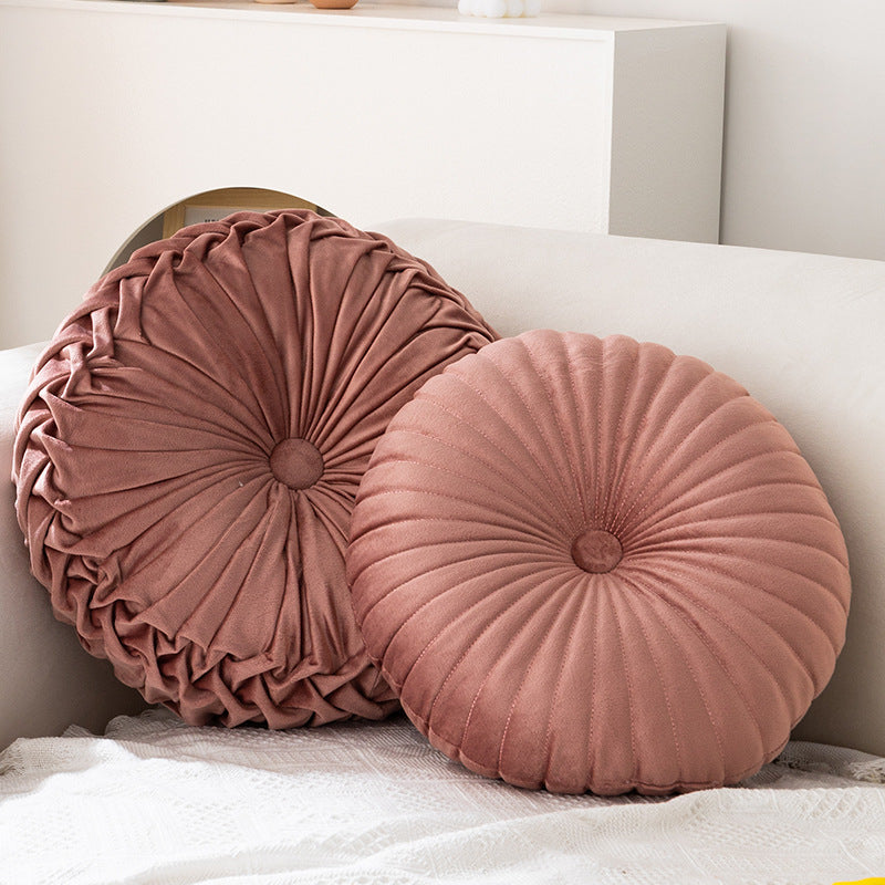 Two round, pleated pink cushions on a white surface.