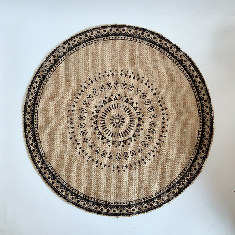 Round beige placemat with black geometric pattern on a white background