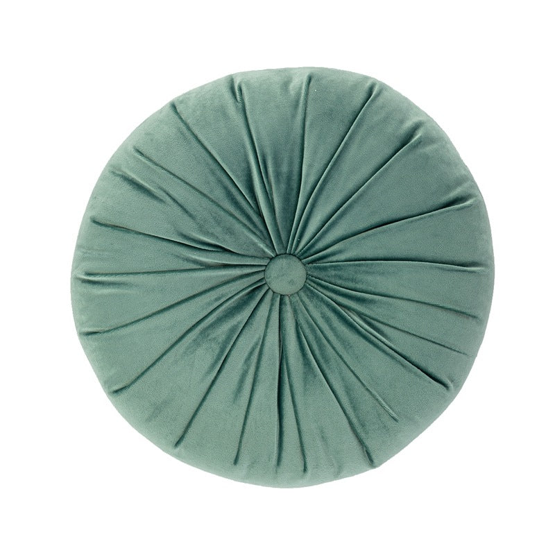 Round green cushion with pleated texture on a white background