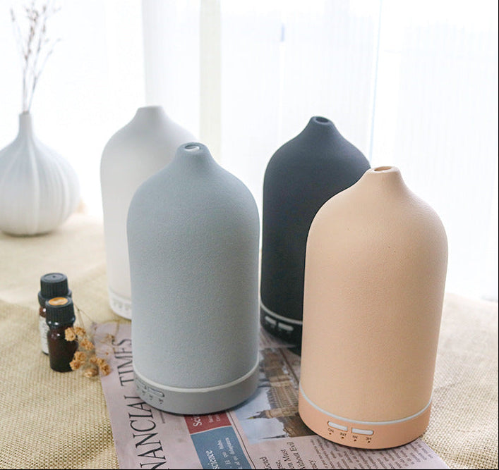 Set of four diffusers in different colors on a table with a newspaper underneath.