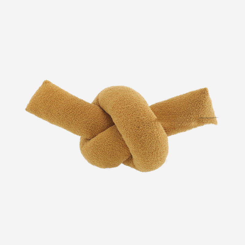 Mustard-colored knot-shaped object on a white background