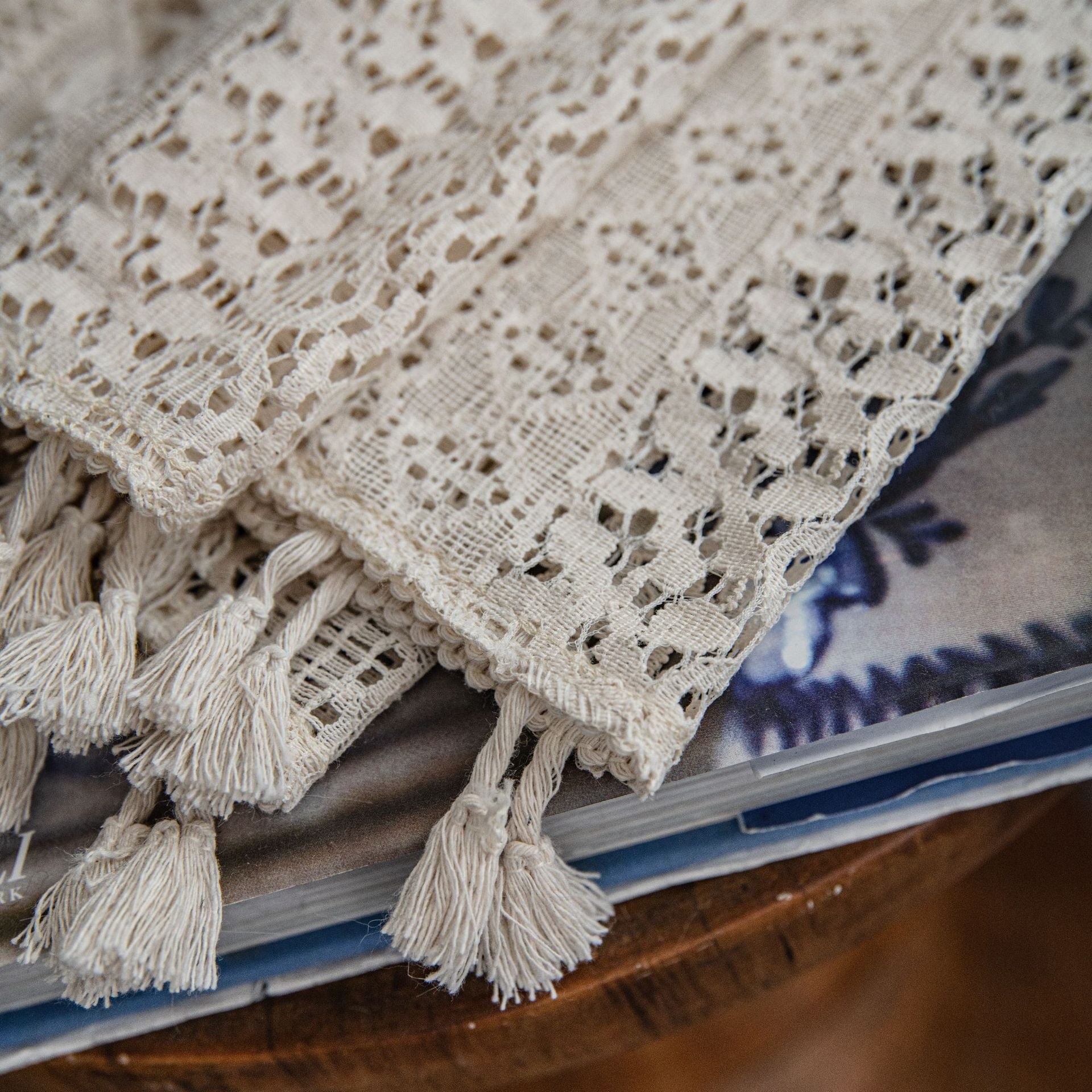 Beige lace fabric with tassels on a stack of books