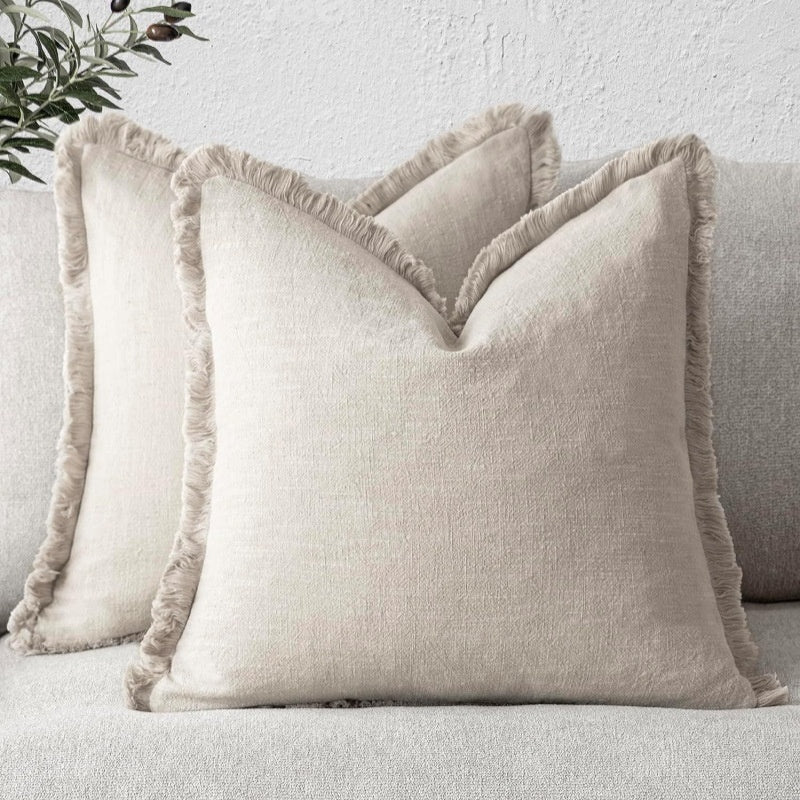 Beige textured pillows with frayed edges on a light gray sofa.