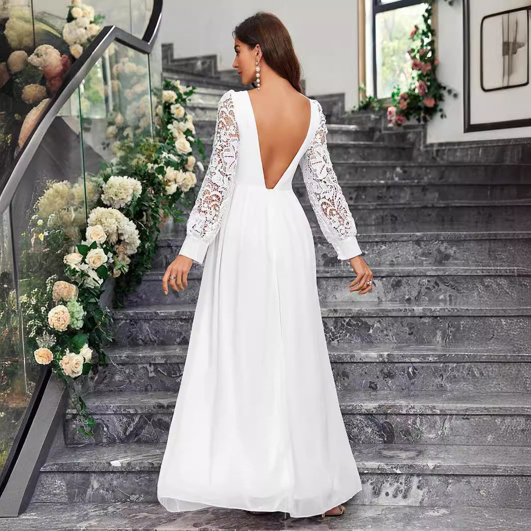 Woman in a white lace dress walking up a decorative staircase with floral arrangements.