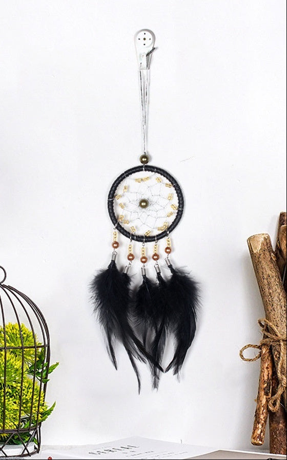 Dreamcatcher hanging on a white wall with decorative elements like plants and birds.