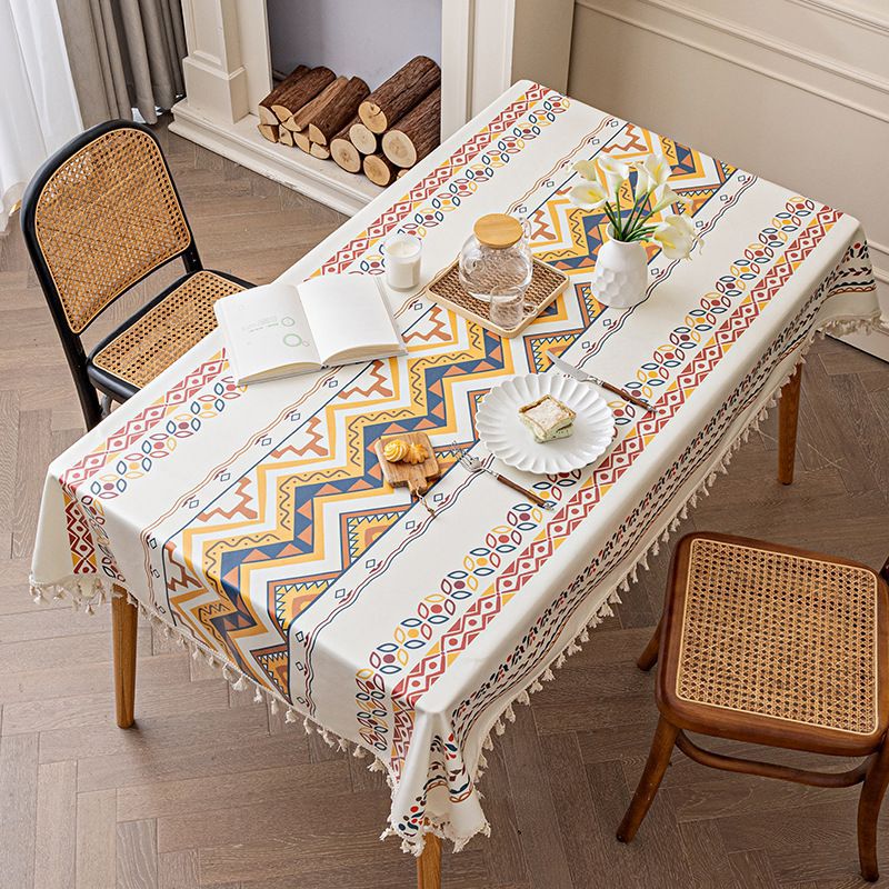 Table with a patterned tablecloth, books, and snacks in a cozy room.