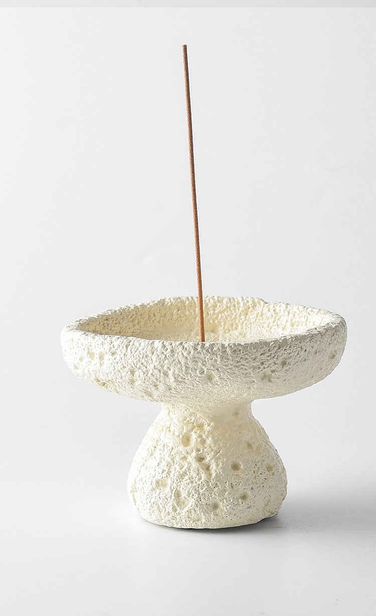 White textured incense holder with a single incense stick on a light gray background