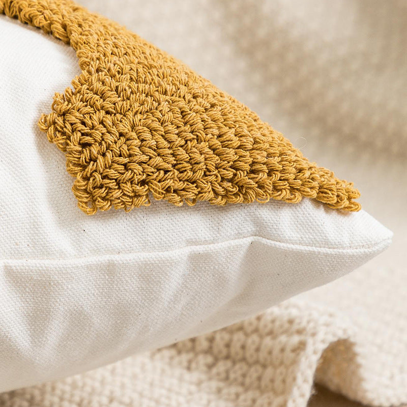 White pillow with a mustard yellow knitted patch on a neutral background