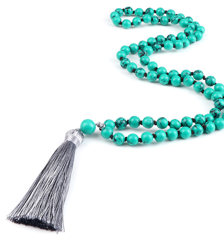 Turquoise beaded necklace with a gray tassel on a white background