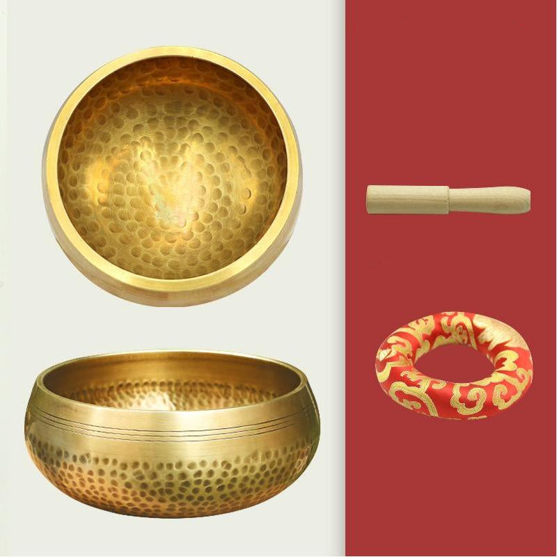 Two brass singing bowls with accessories on a white background