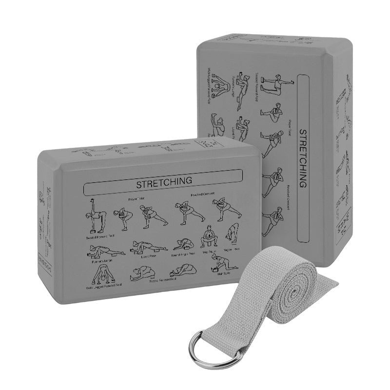 Two gray yoga blocks with stretching illustrations and a gray yoga strap on a white background