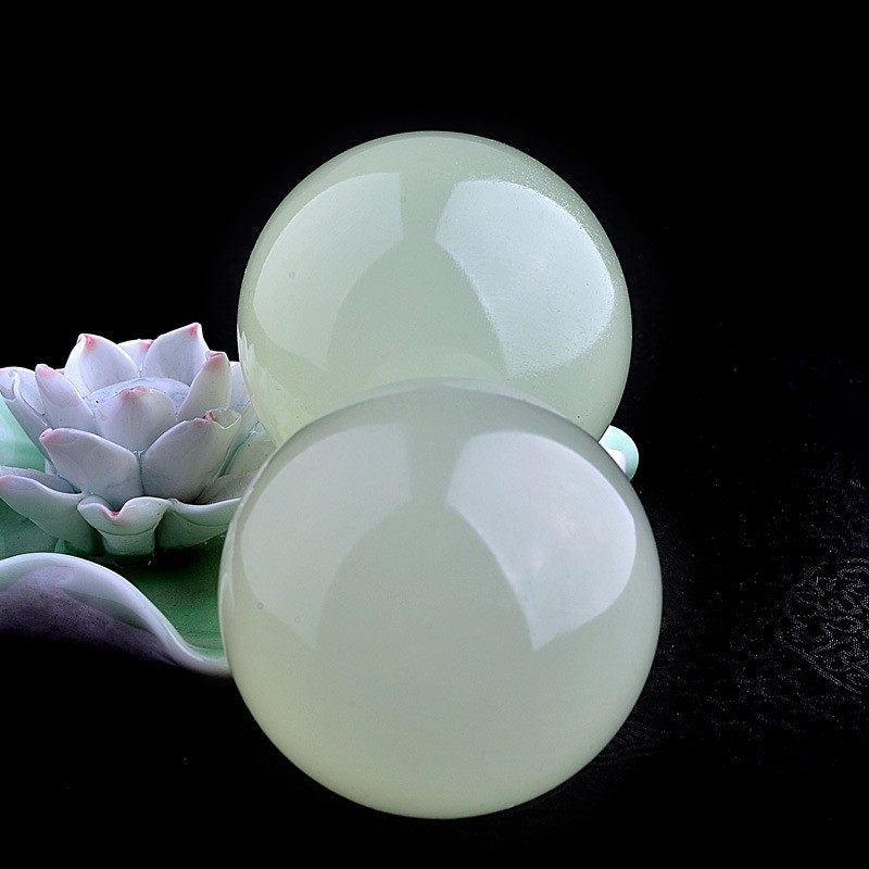 Two green jade spheres with a succulent plant on a dark background