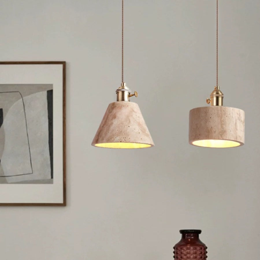 Two pendant lights hanging from the ceiling with a neutral wall and framed picture in the background.