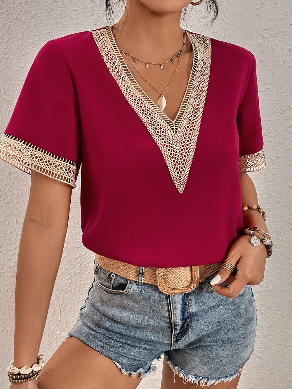 Red top with lace details worn by a person against a neutral background