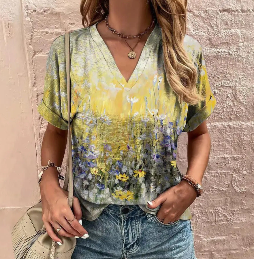 Woman wearing a floral blouse with a beige bag against a textured wall.