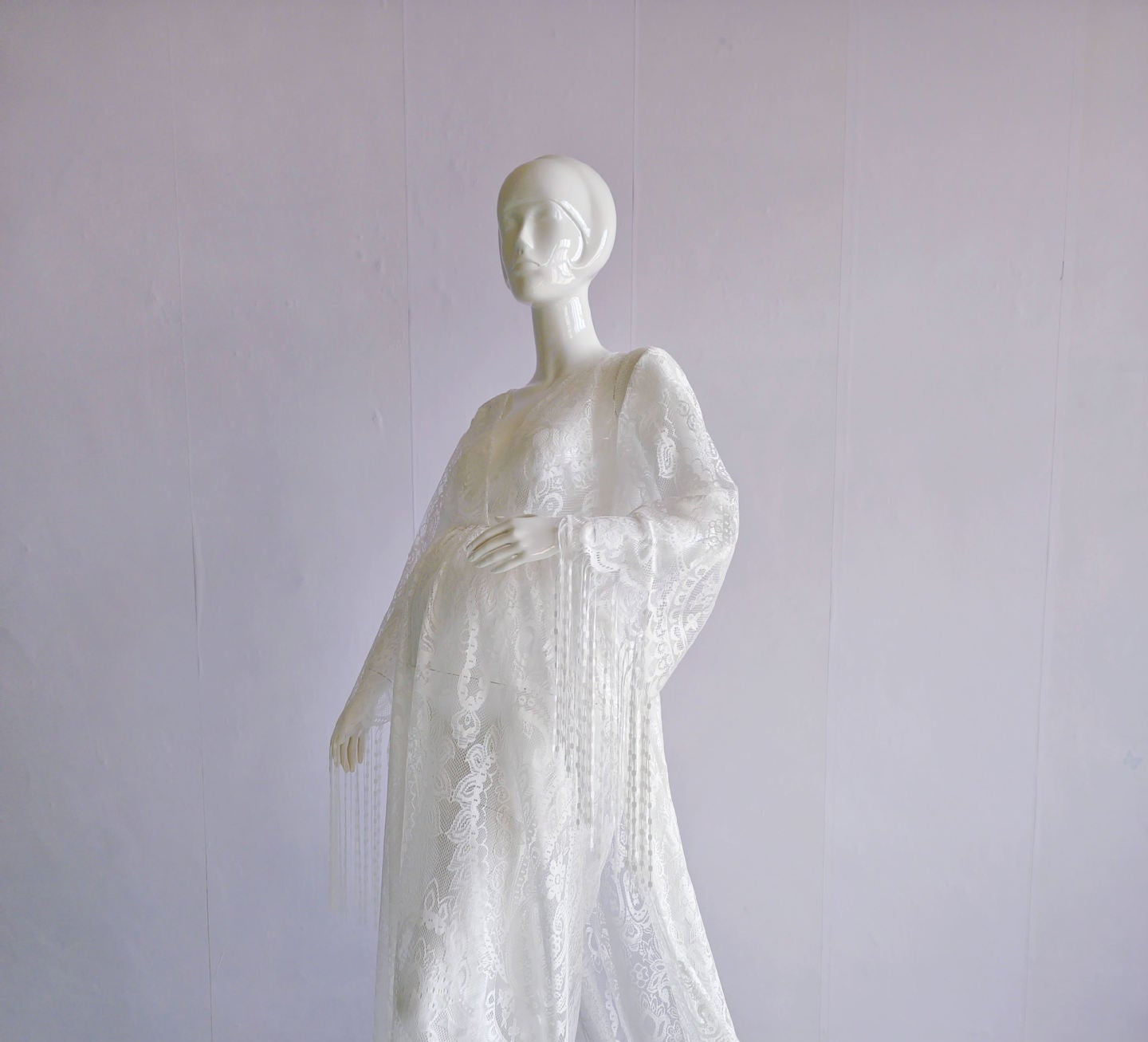 Mannequin wearing a white lace dress on a plain background