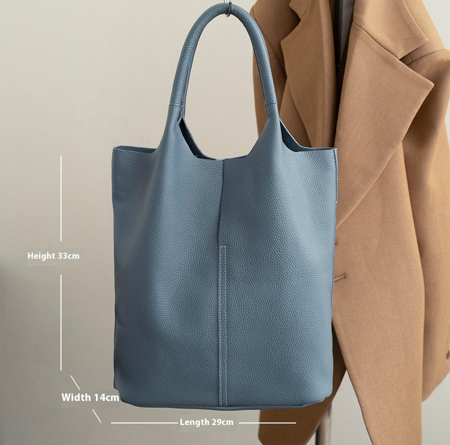 Blue leather handbag with measurements and material details on a neutral background