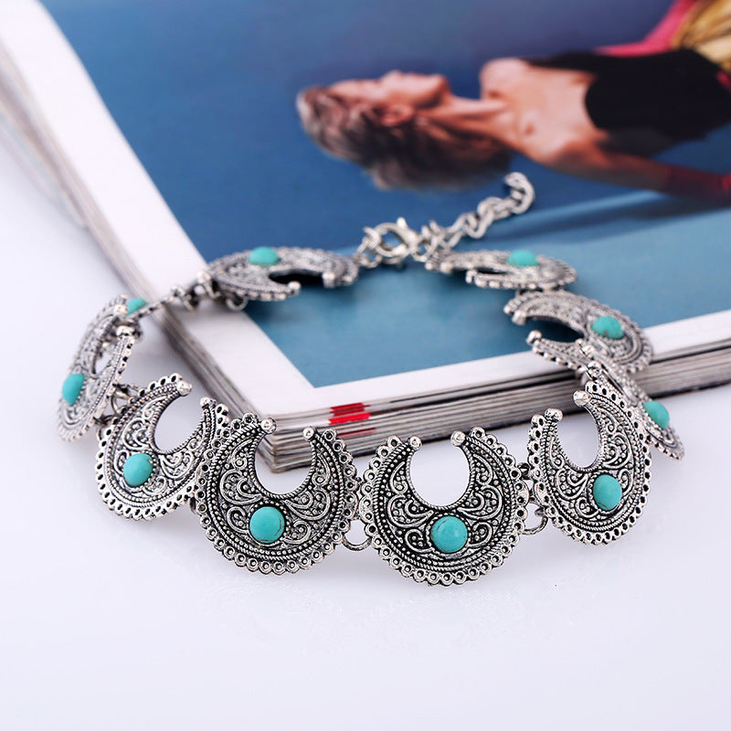 Silver necklace with turquoise stones on a white surface