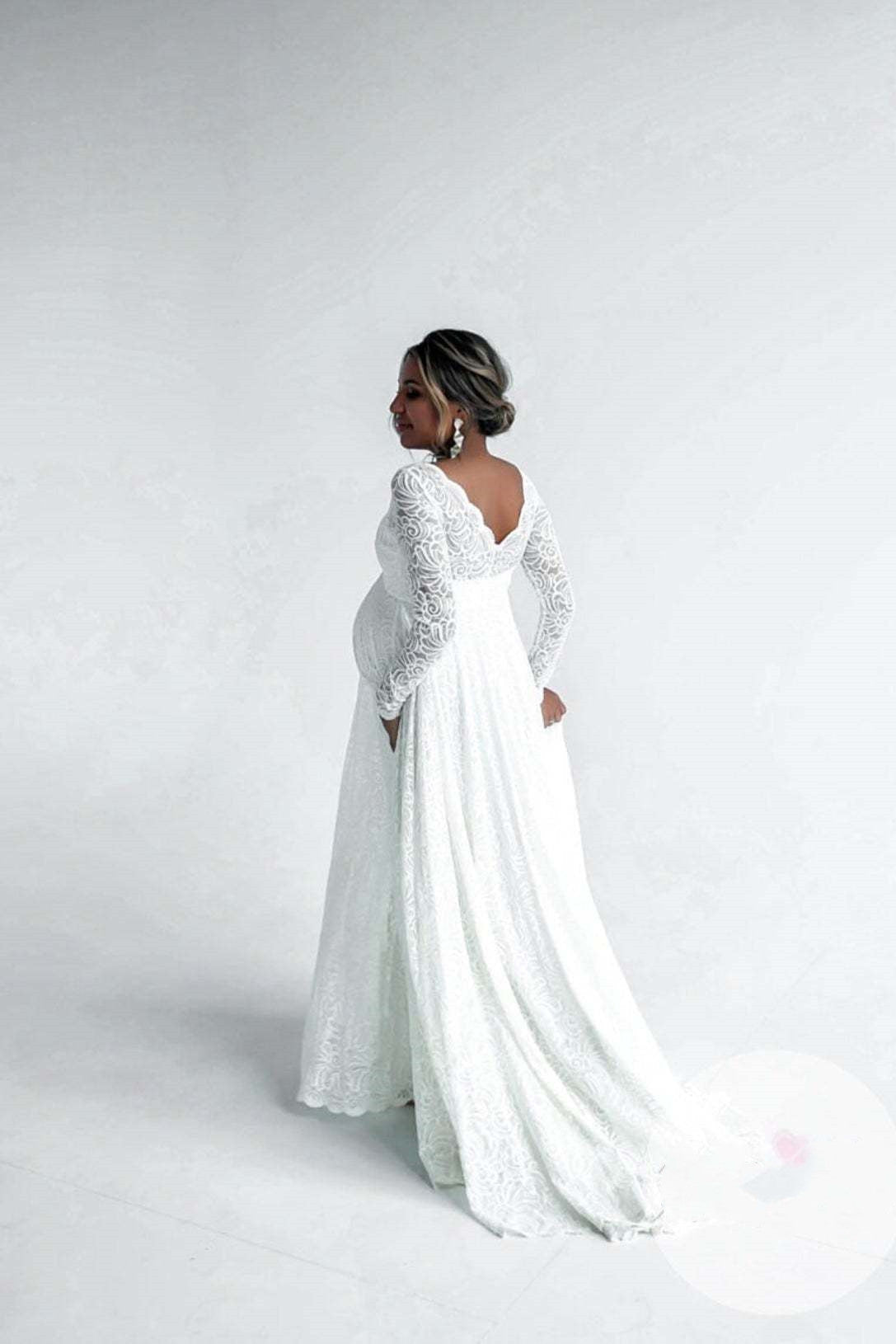 Woman wearing a white lace wedding dress on a plain background